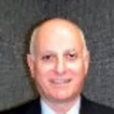 A bald man in a suit and tie is smiling for the camera.