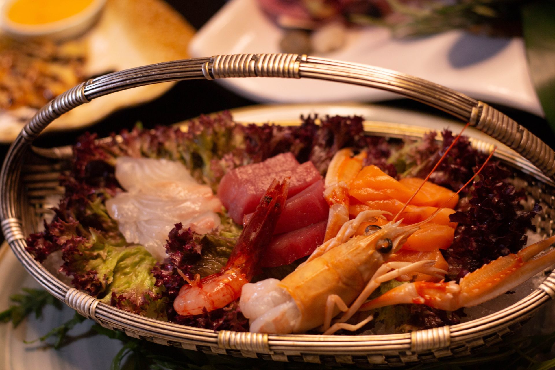 Cestino di sushi e sashimi assortiti con verdure su un tavolo