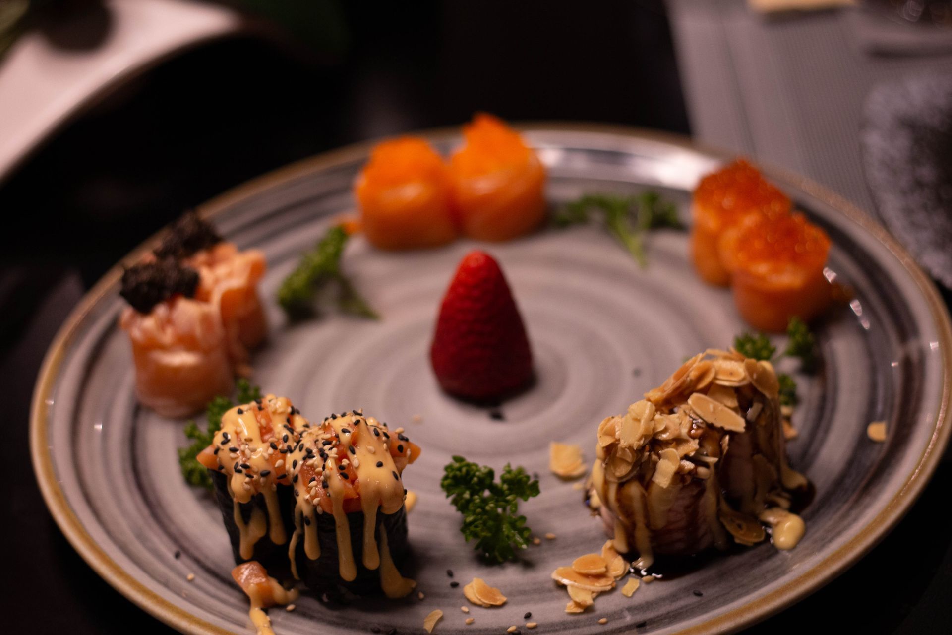 Dessert gourmet impiattato con frutta assortita e guarnizioni su un piatto grigio.