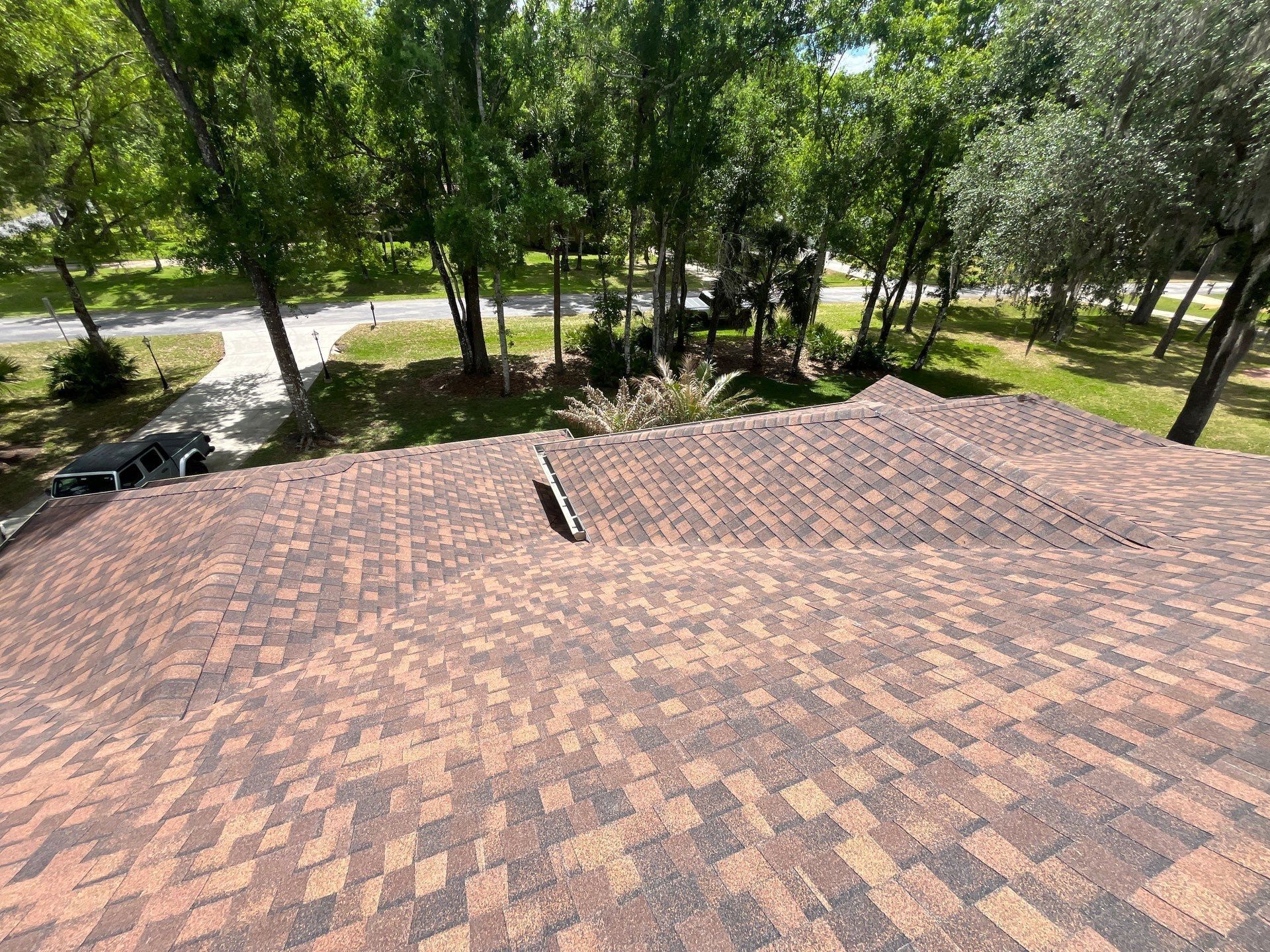 Close-up view of a professionally installed CertainTeed Landmark PRO Burnt Sienna shingle roof with ridge vent system in Zephyrhills, Florida.