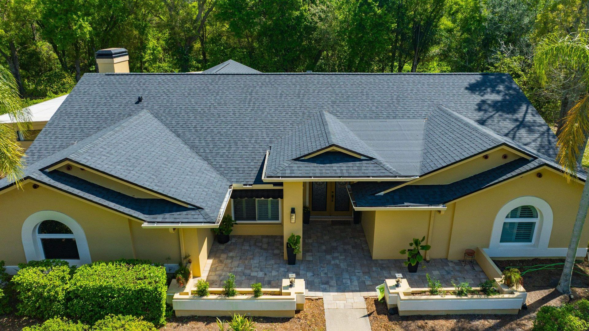 Front aerial view of a home with a new CertainTeed Landmark Moire Black architectural shingle roof in Hammock Woods, Odessa, FL.