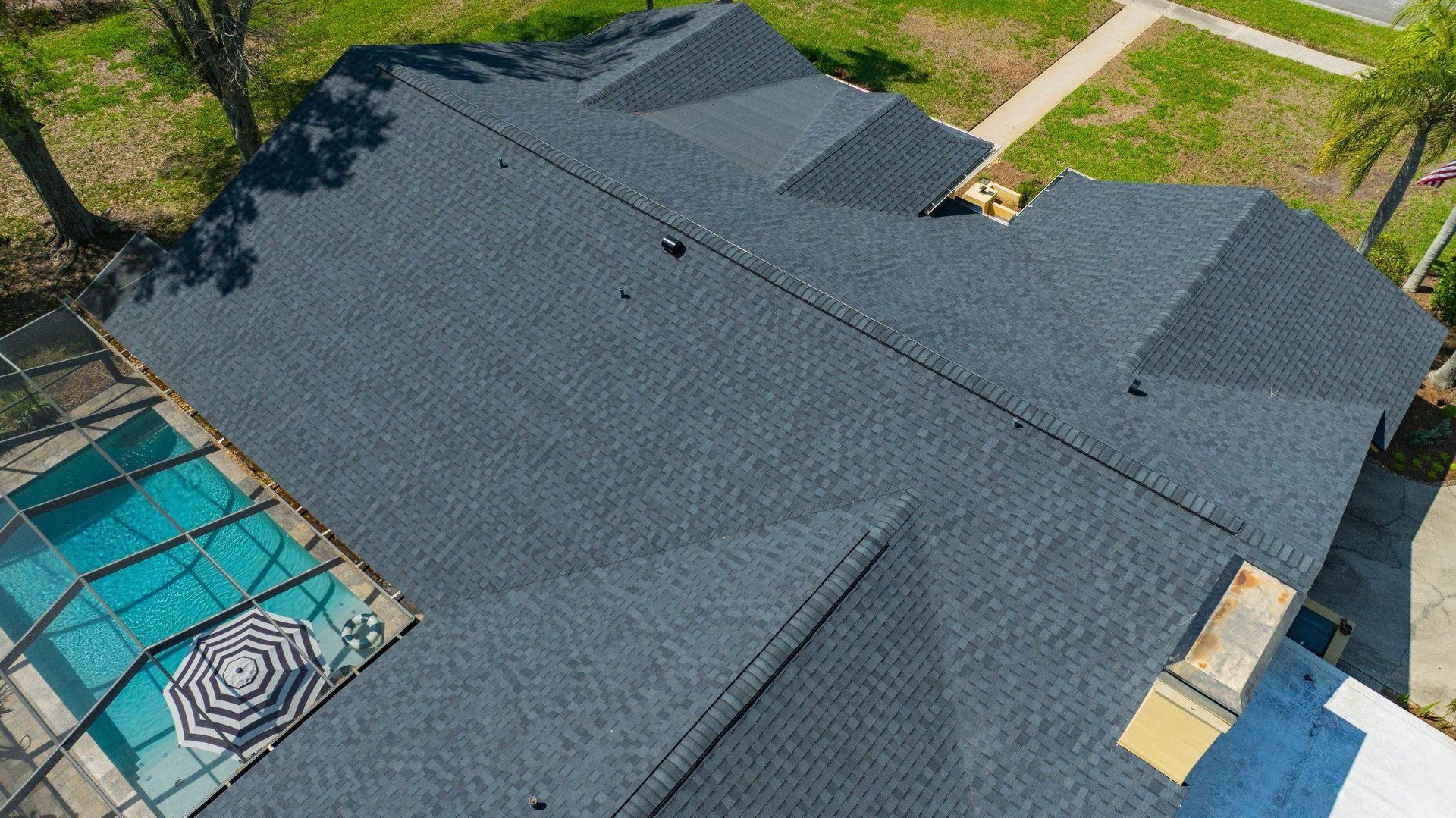 Close aerial view of a CertainTeed Landmark Moire Black architectural shingle roof with ridge cap and roof ventilation in Hammock Woods, Odessa, FL.