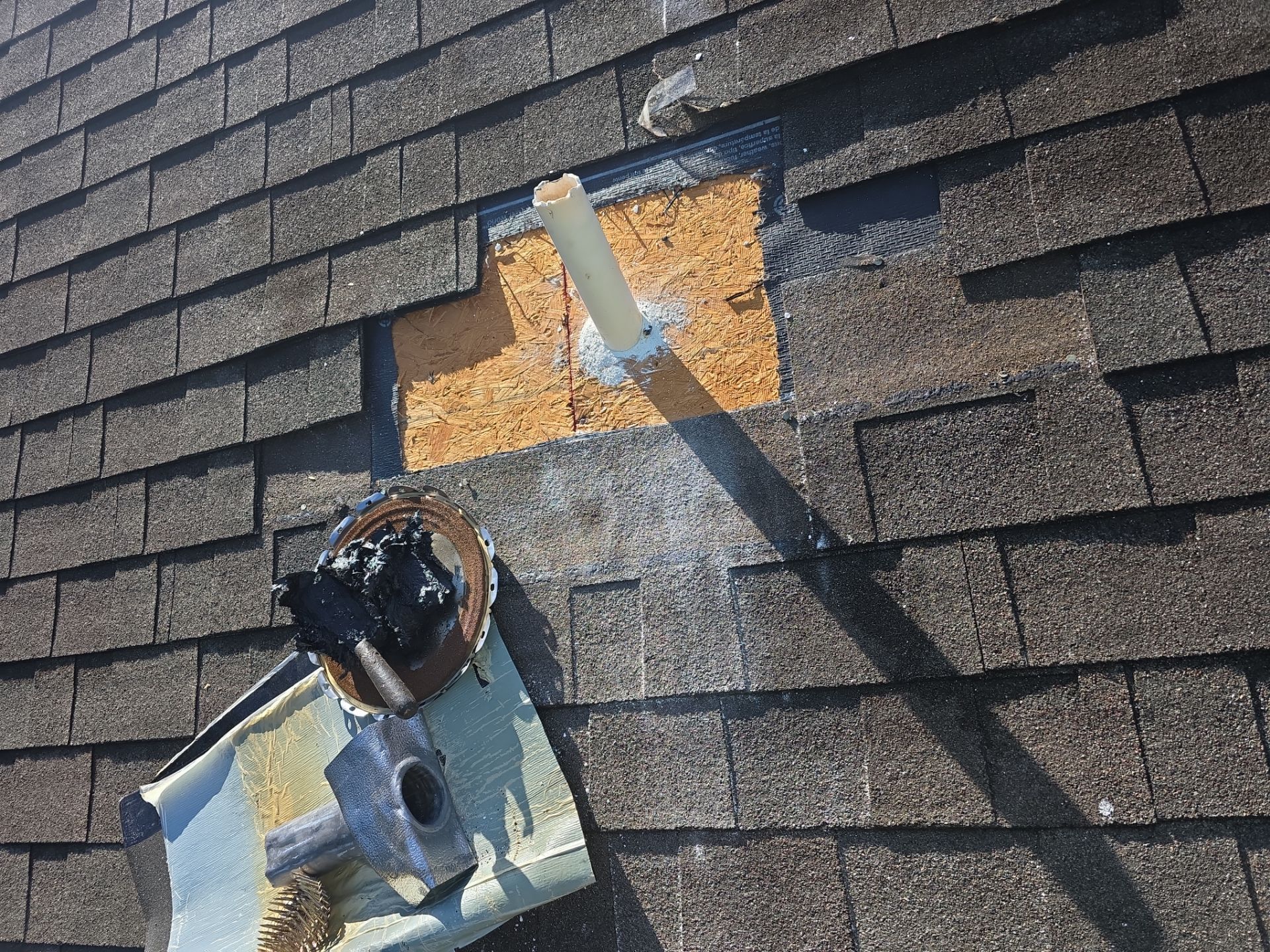 Shingles and existing roofing materials removed around a damaged pipe penetration as part of a localized shingle roof repair in Wesley Chapel.