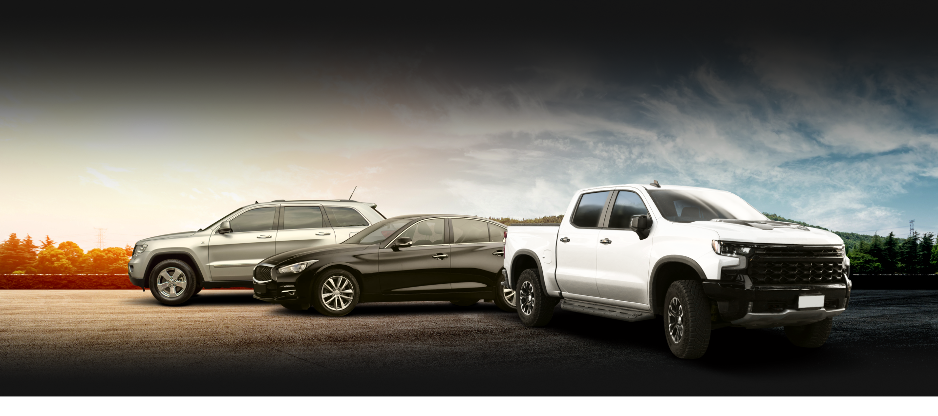 Three vehicles, SUV, sedan, and pickup truck, parked on a paved surface, against a cloudy sky background.