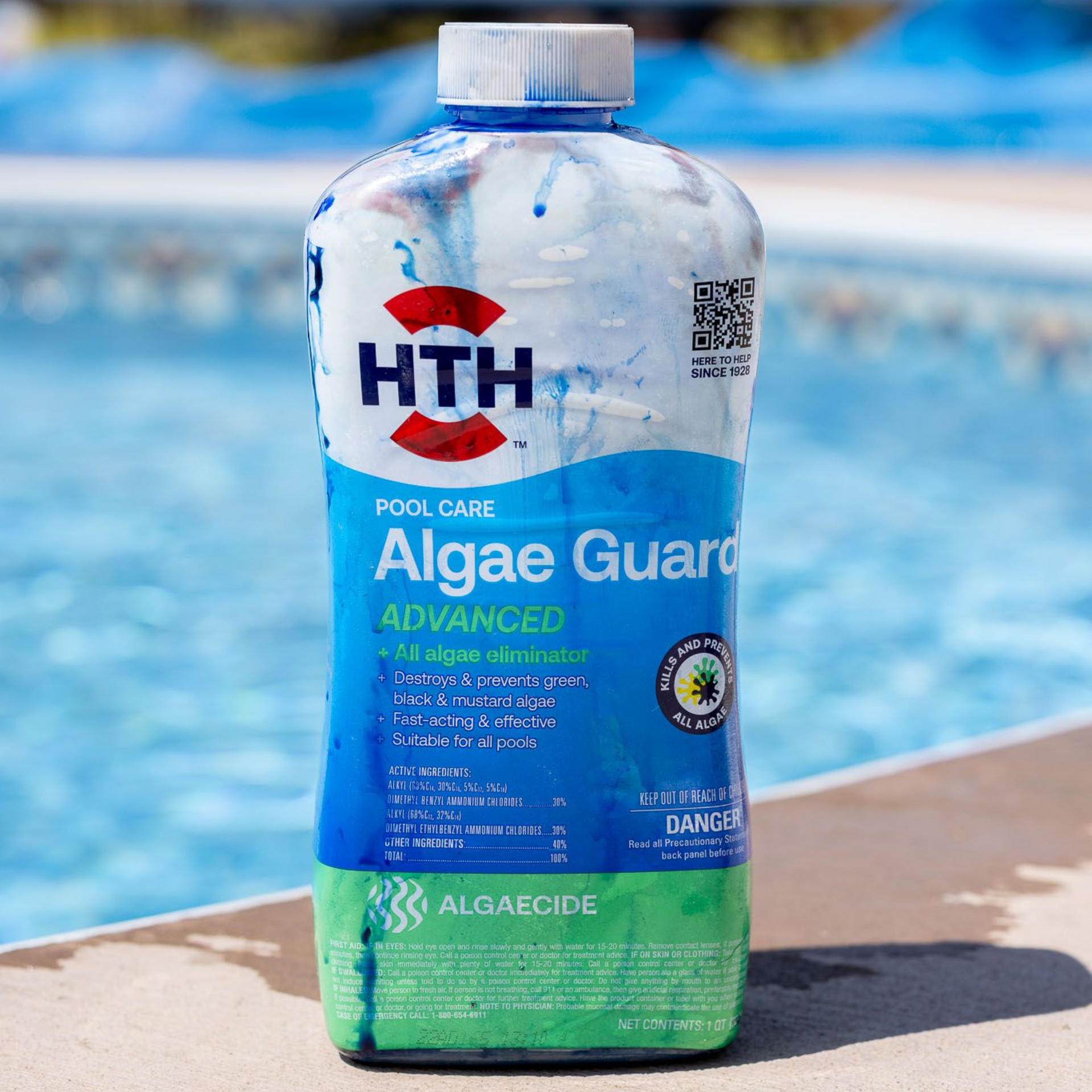 A swimming pool with a vacuum cleaner, hose, and brushes on the edge.