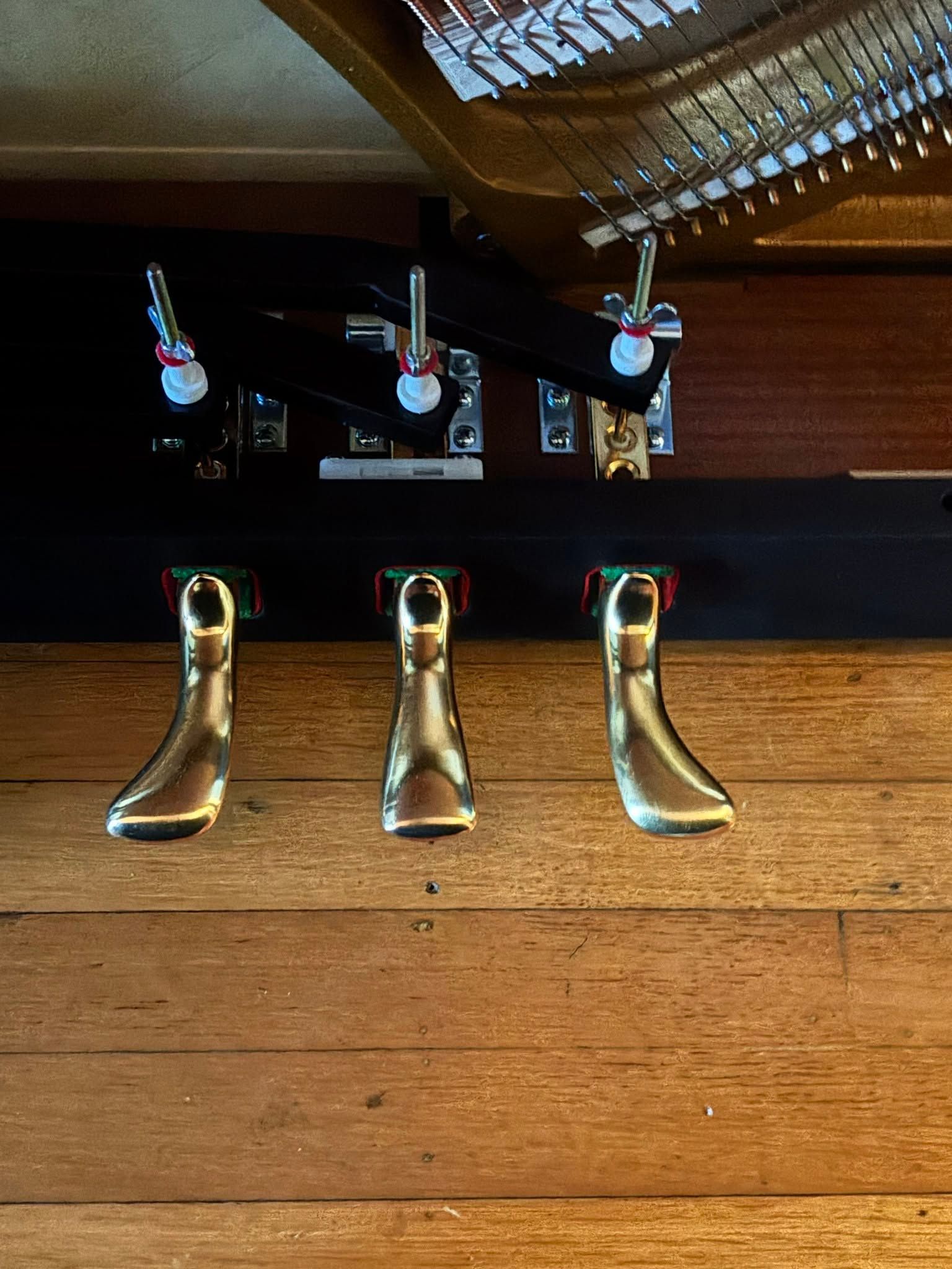 Three polished brass pull handles on a wooden door with black lock hardware above them