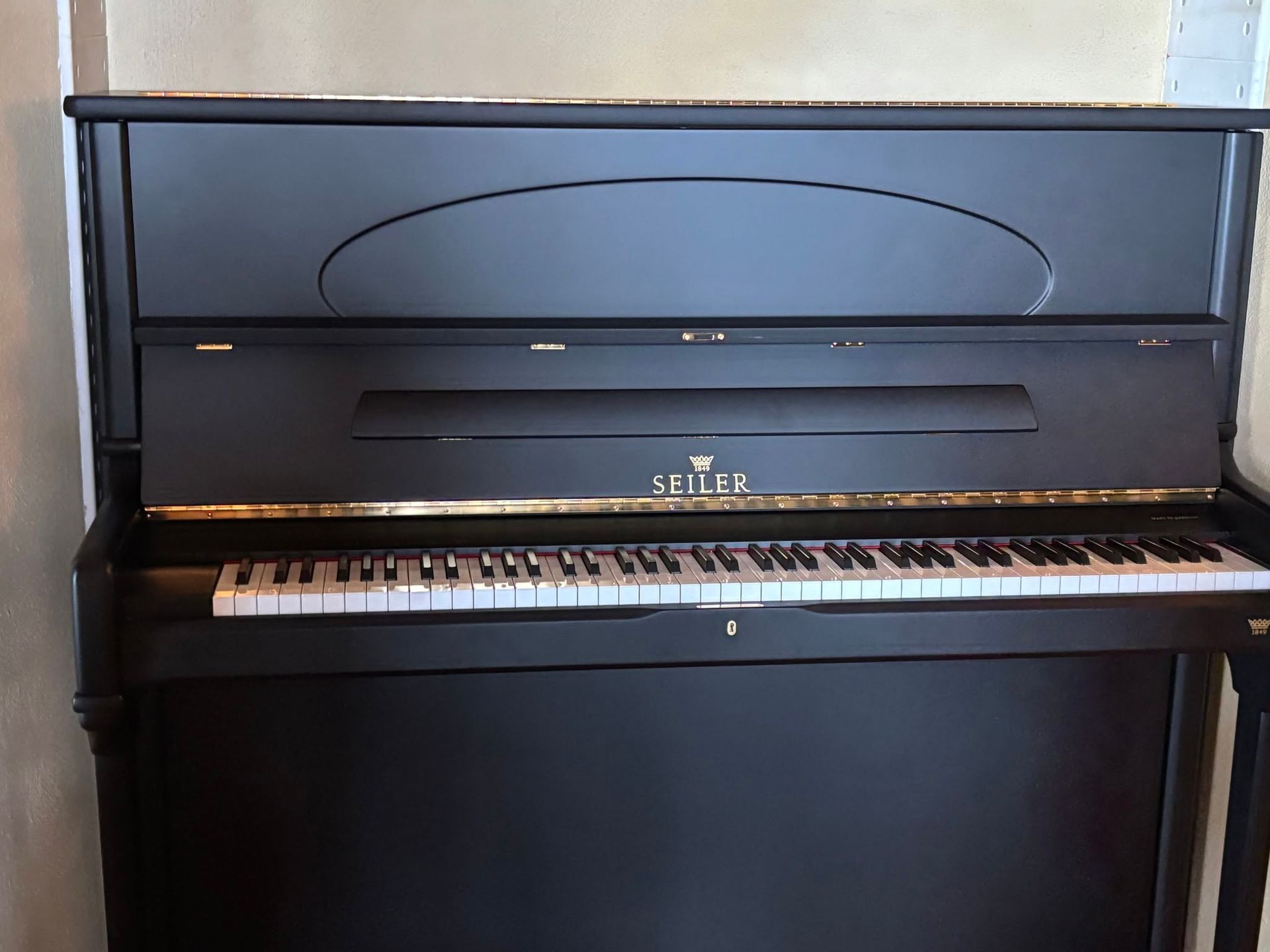 Black upright piano with a closed fallboard and matching bench in a room