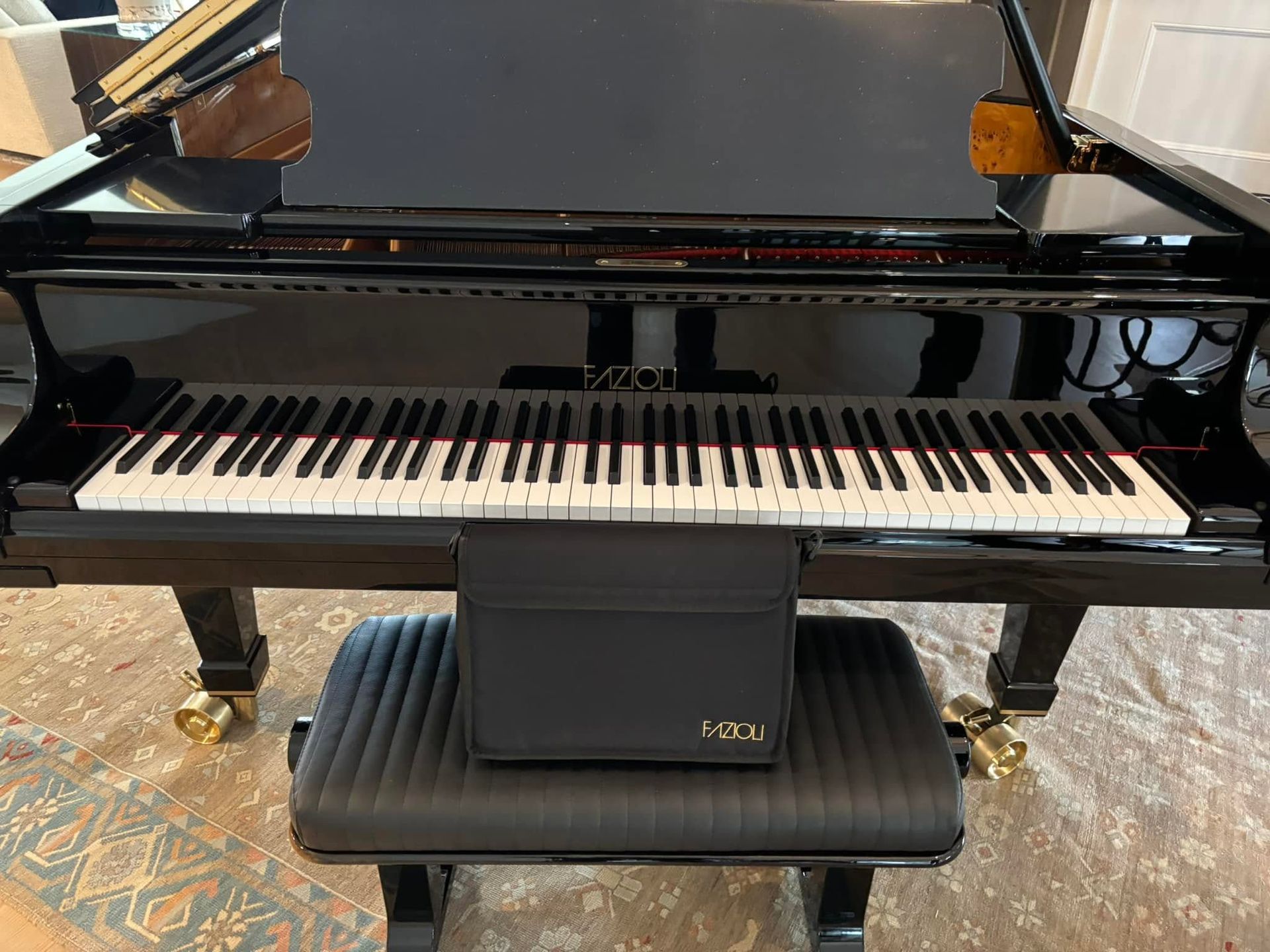 Black grand piano with a matching bench and music stand in a room, with a black cushion on the bench.
