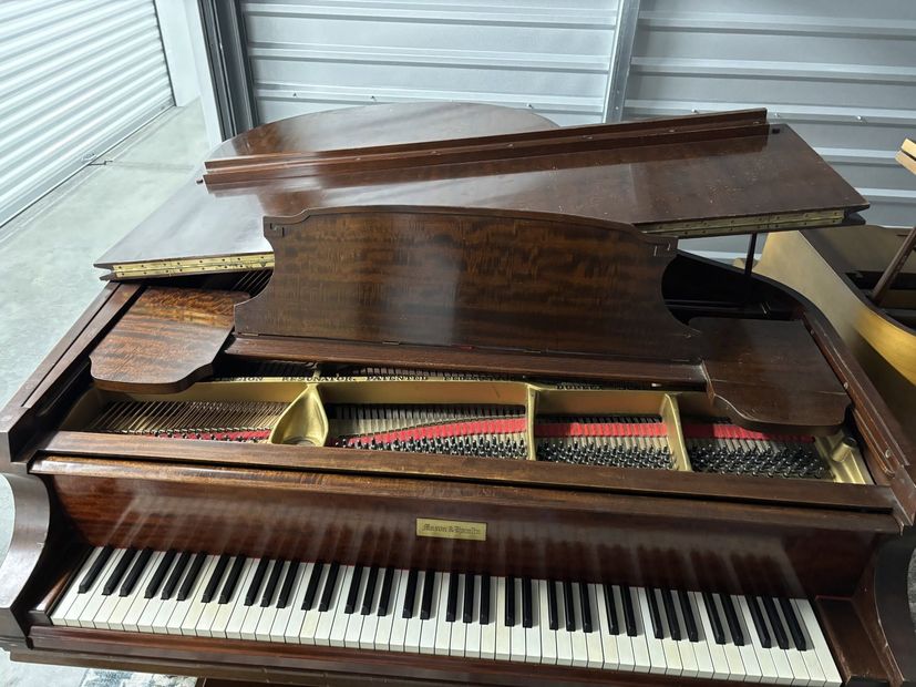 Brown upright piano with lid open, showing strings and keys in a storage area