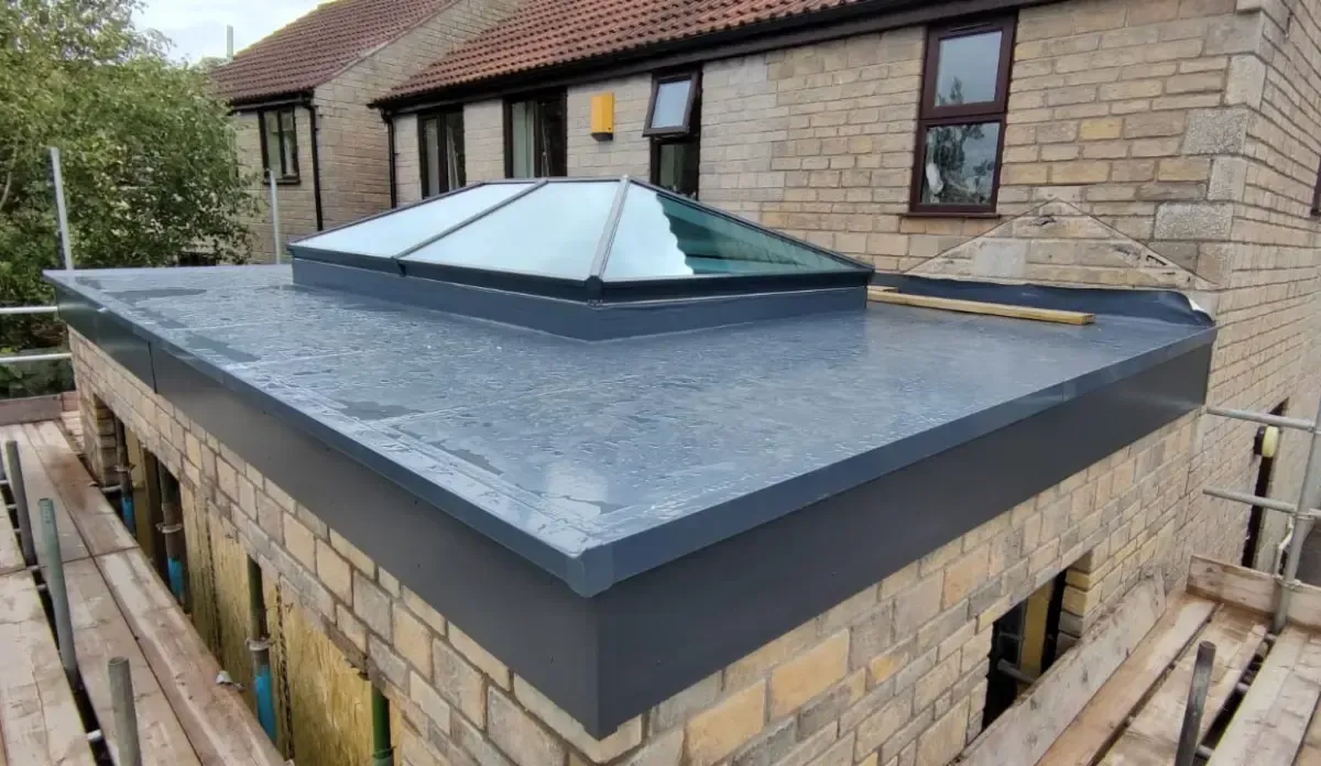 Flat roof with dark waterproofing and a central skylight on a brick building