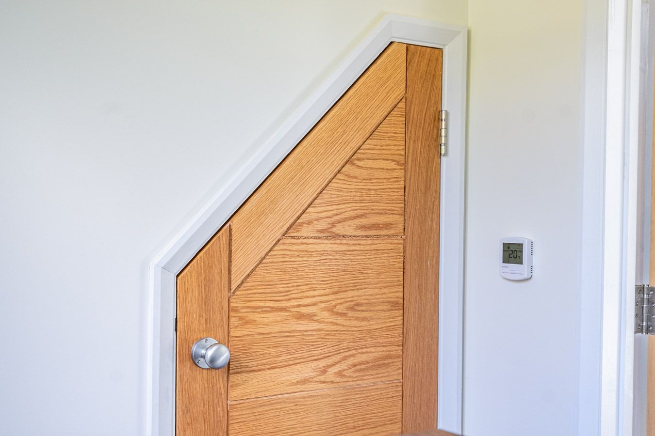 Wooden attic door with silver knob in a white wall corner