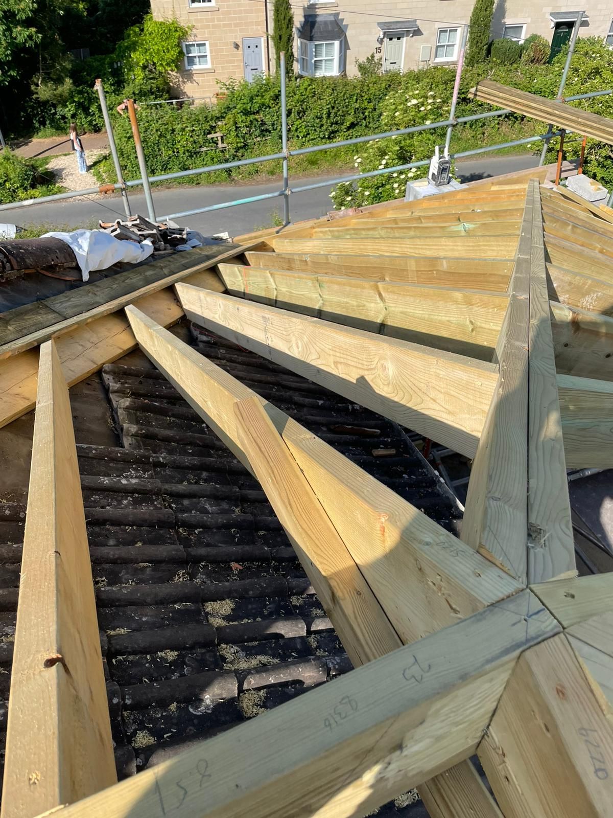 Wooden roof frame under construction with exposed rafters and scaffolding on a residential building