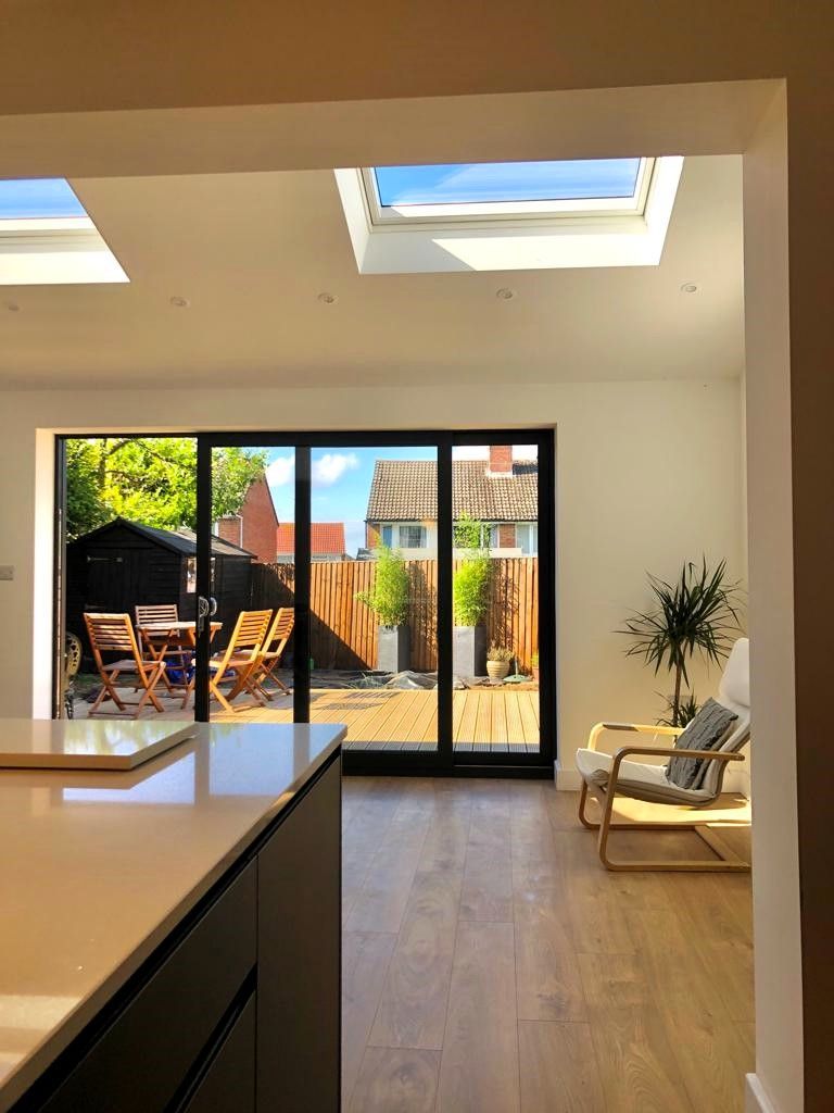 Bright living room with skylights, sliding glass doors, patio furniture, and a chair by the window