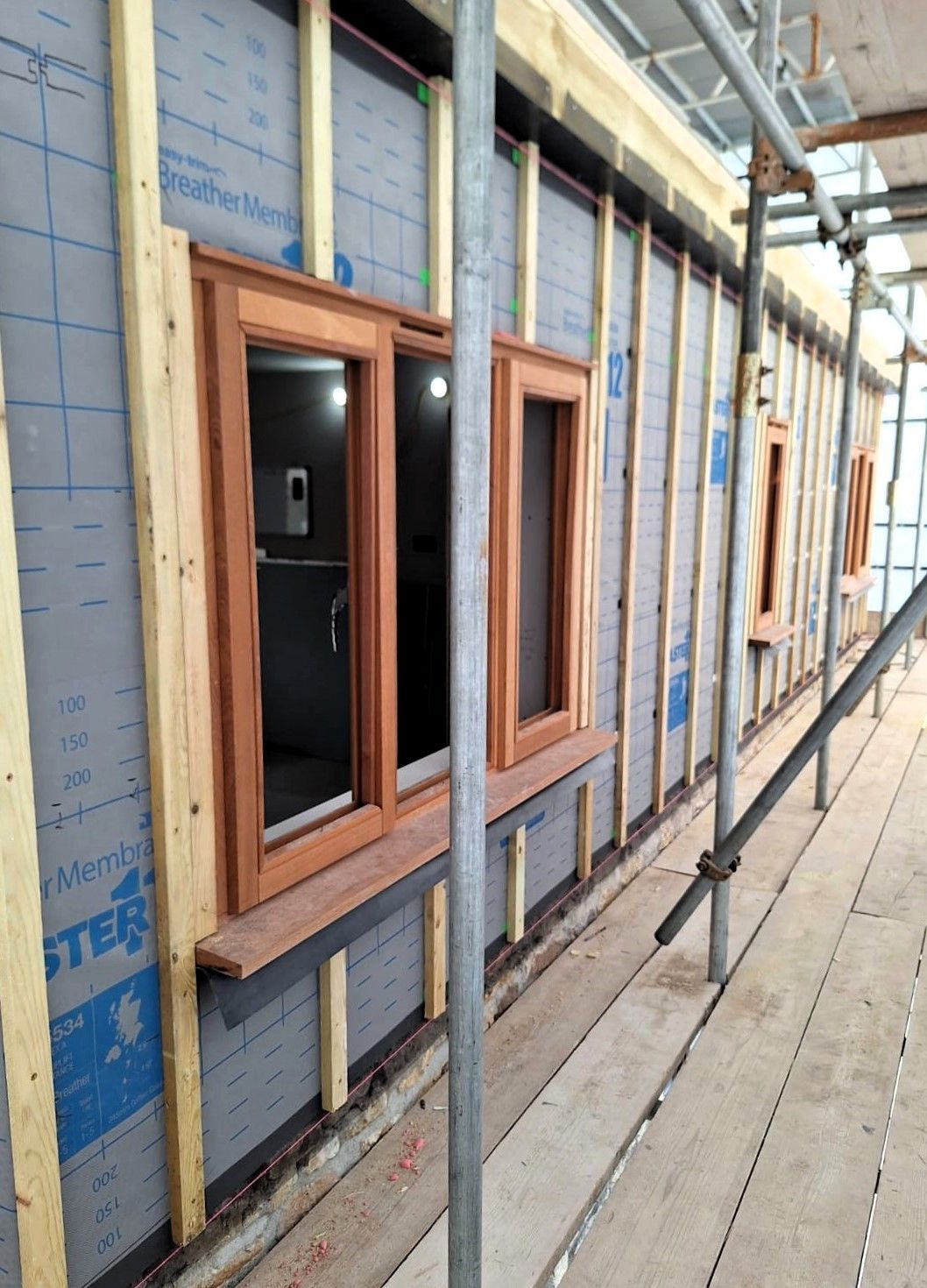 Wood-framed windows installed on an insulated exterior wall at a construction site