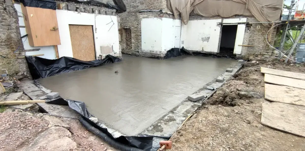 Collapsed building with a flooded concrete foundation and debris around the site