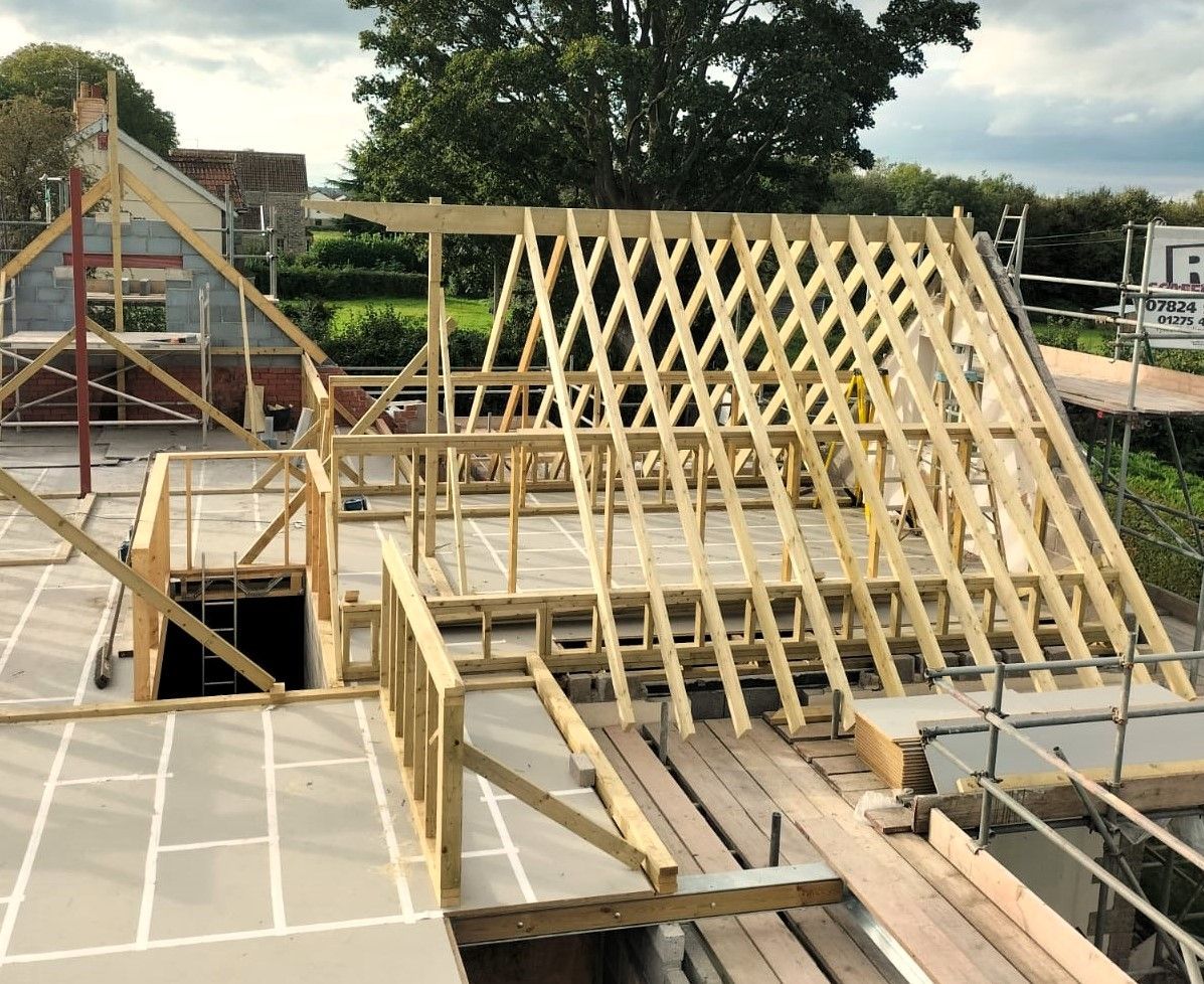 Wooden roof trusses under construction on a house frame at a building site