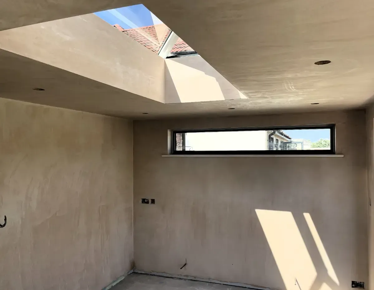 Bare unfinished room with beige walls, skylight opening, and a narrow horizontal window.