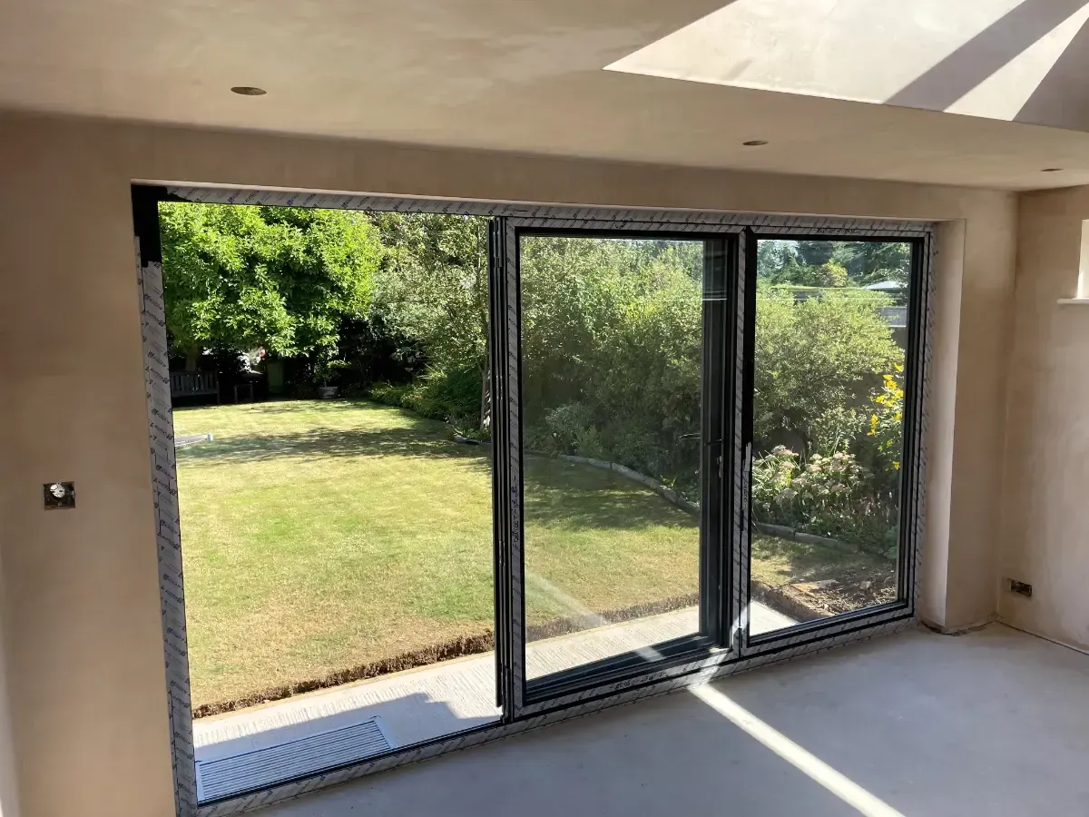 Modern room with large sliding glass doors opening to a sunny backyard and lawn.
