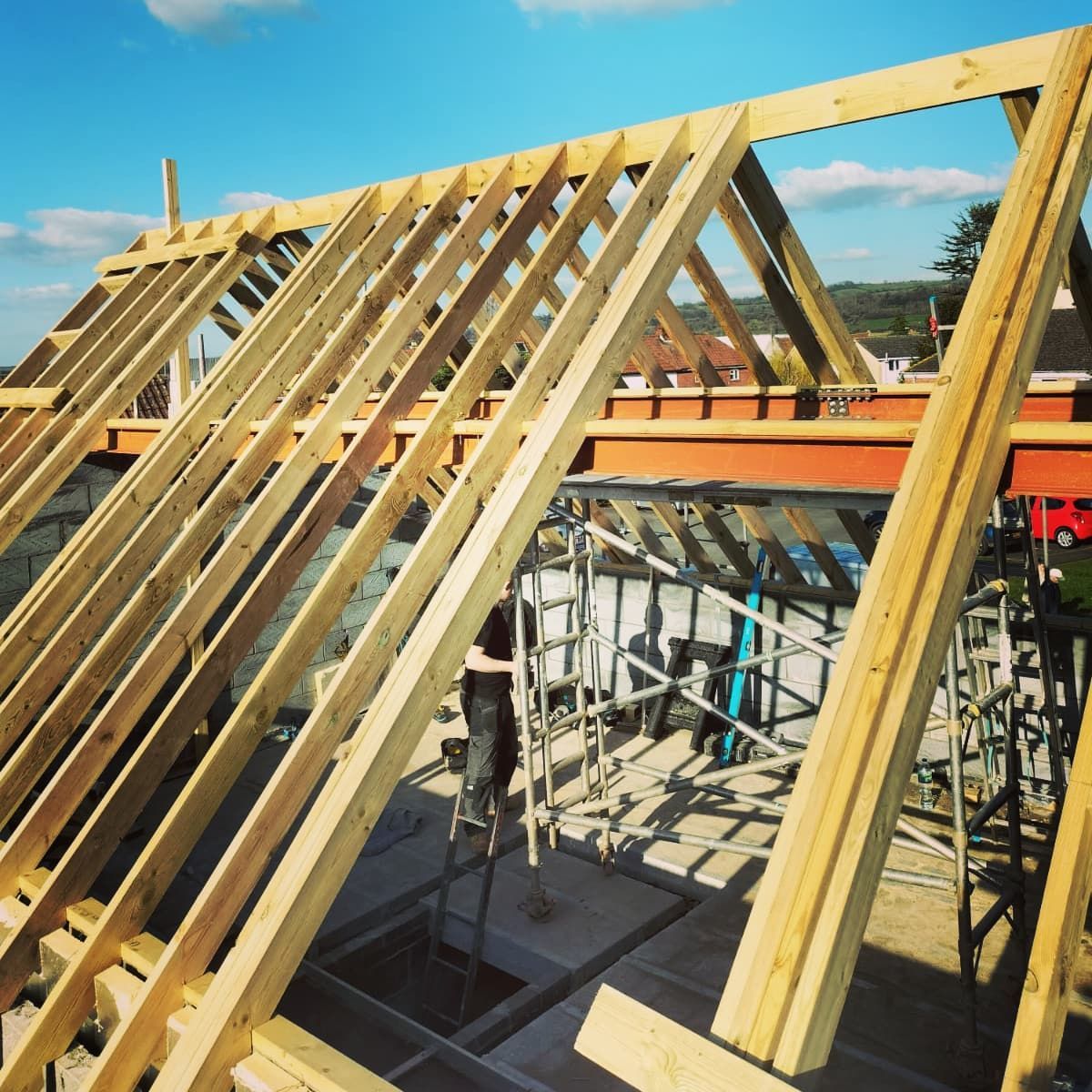 Wooden roof trusses under construction on a building site under a blue sky