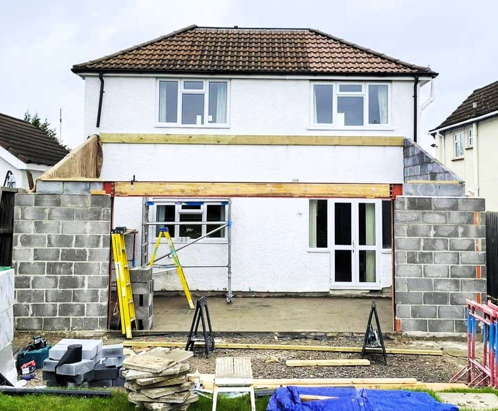 House under renovation with brick retaining walls, scaffolding, and ladders in the front yard