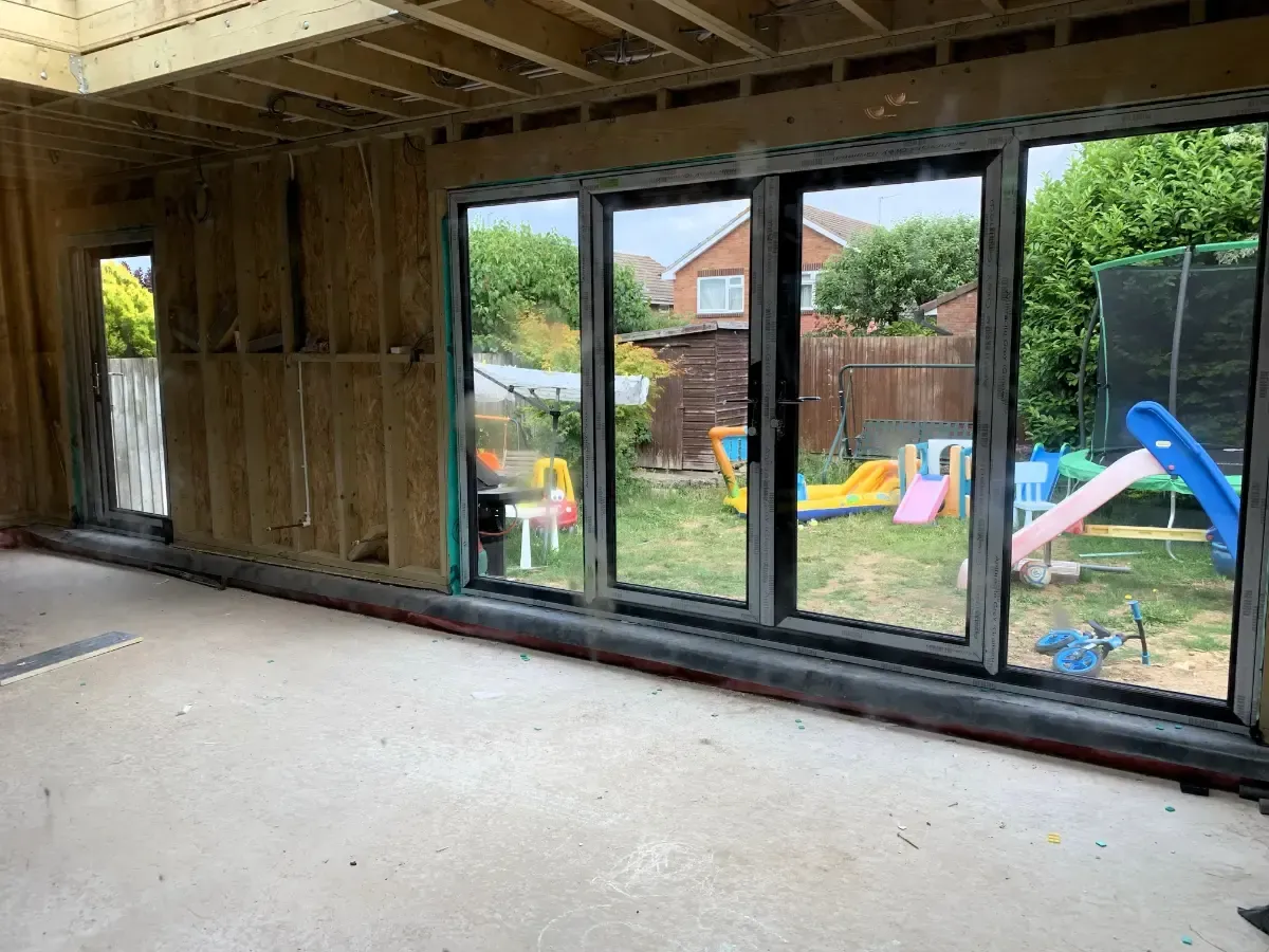 Unfinished room with large sliding glass doors opening to a backyard with a trampoline and play slide.