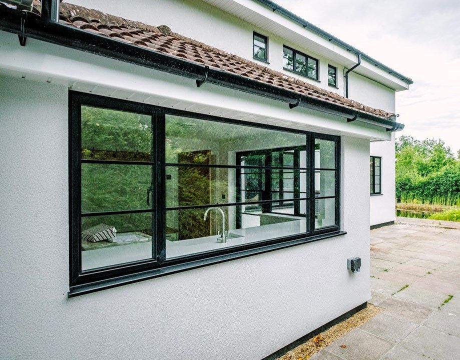 White house exterior with large black-framed bay window and paved driveway on the side