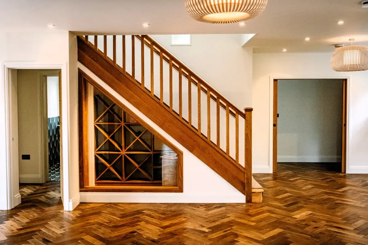 Modern living room with wooden staircase, wine rack, and herringbone wood floor