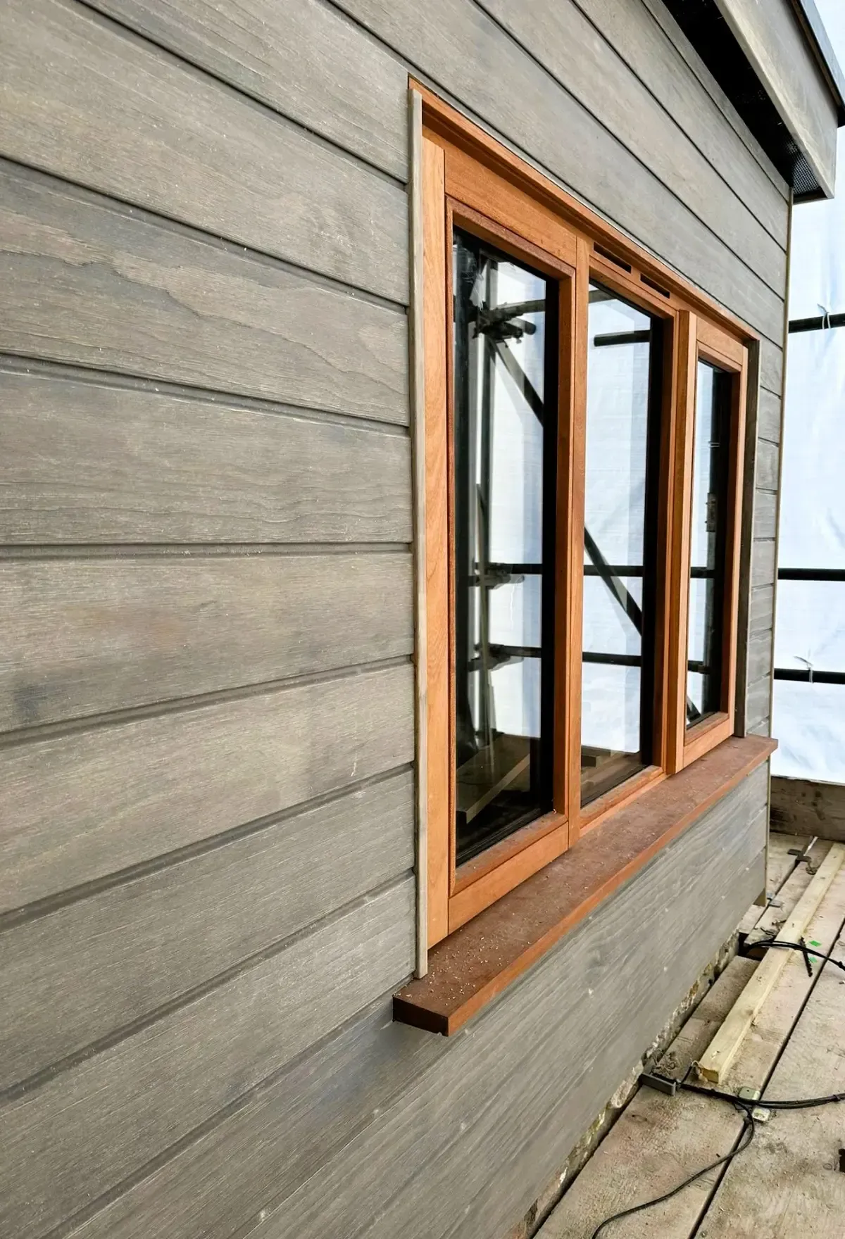 Wooden-framed window in gray exterior siding on a house wall