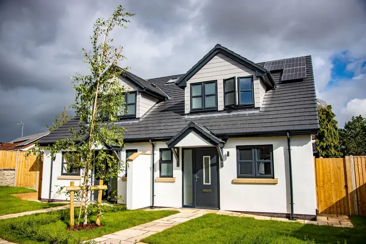 White two-story house with gray roof and front lawn on a cloudy day