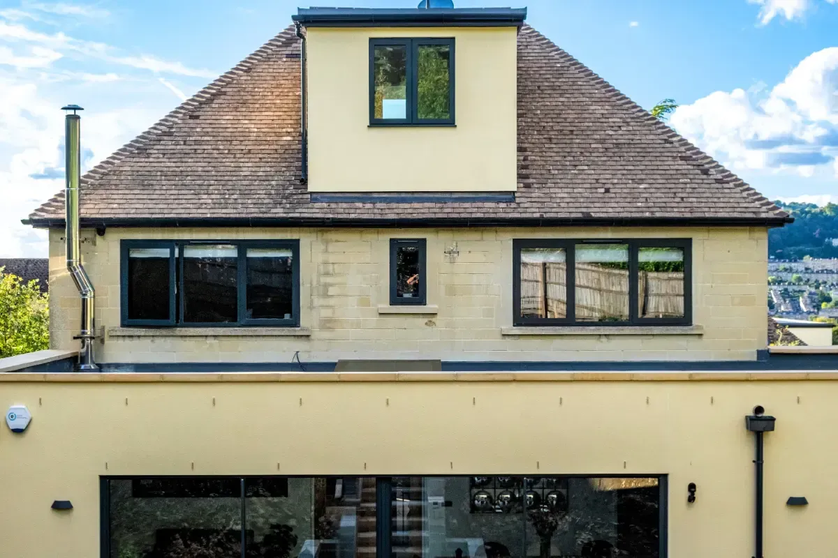 Front view of a cream-colored house with a steep tiled roof and black-trimmed windows