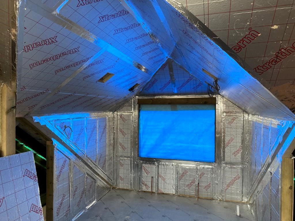Attic wall with blue-lit window and reflective insulation panels