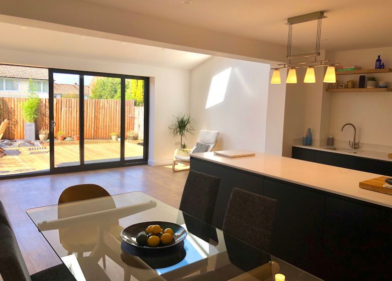 Modern open-plan kitchen and dining area with sliding glass doors to a patio and warm pendant lights