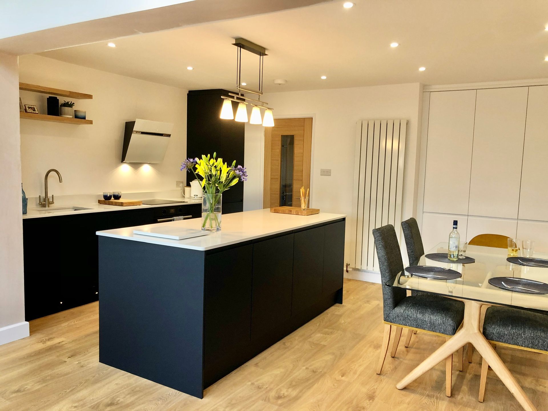 Modern kitchen and dining area with black island, pendant lights, and wooden chairs