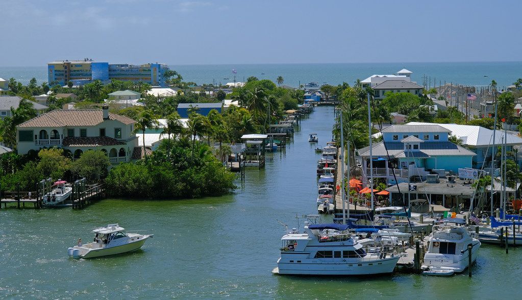 A few boats are docked in a harbor with houses in the background