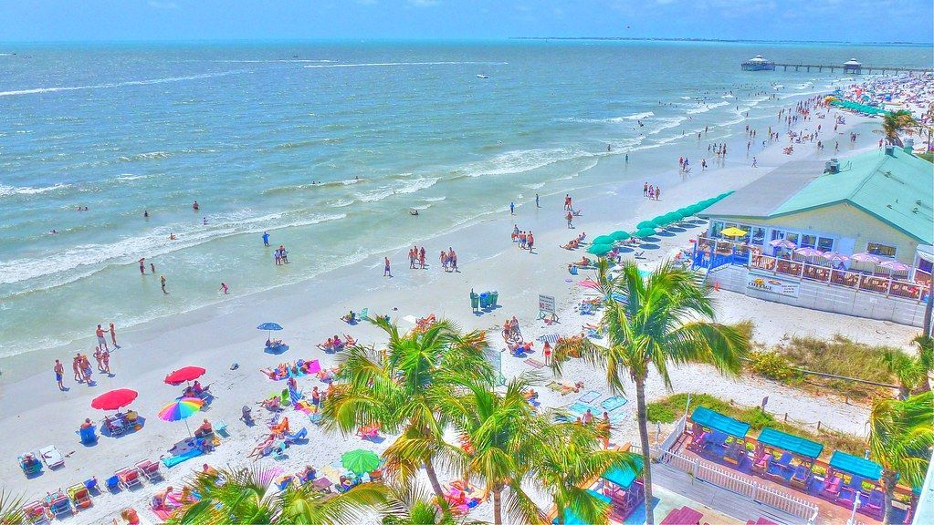 An aerial view of a beach filled with people and umbrellas.