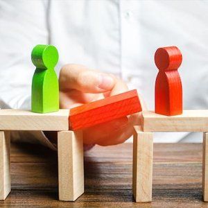 A person is holding a piece of wood between two wooden figures.