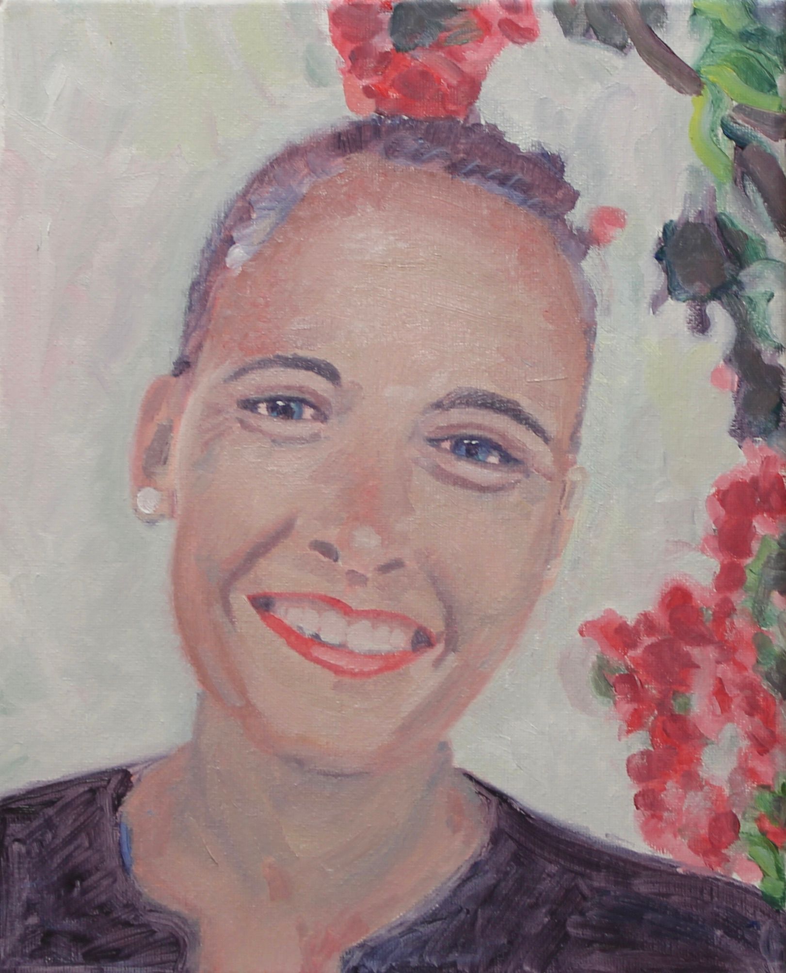 Lachende vrouw met geschoren hoofd, gekleed in een zwarte top, met rode bloemen op de achtergrond.