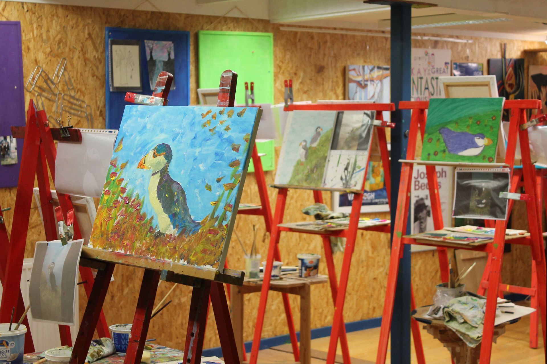 Een schilderij van een vogel staat op een ezel in een kunststudio