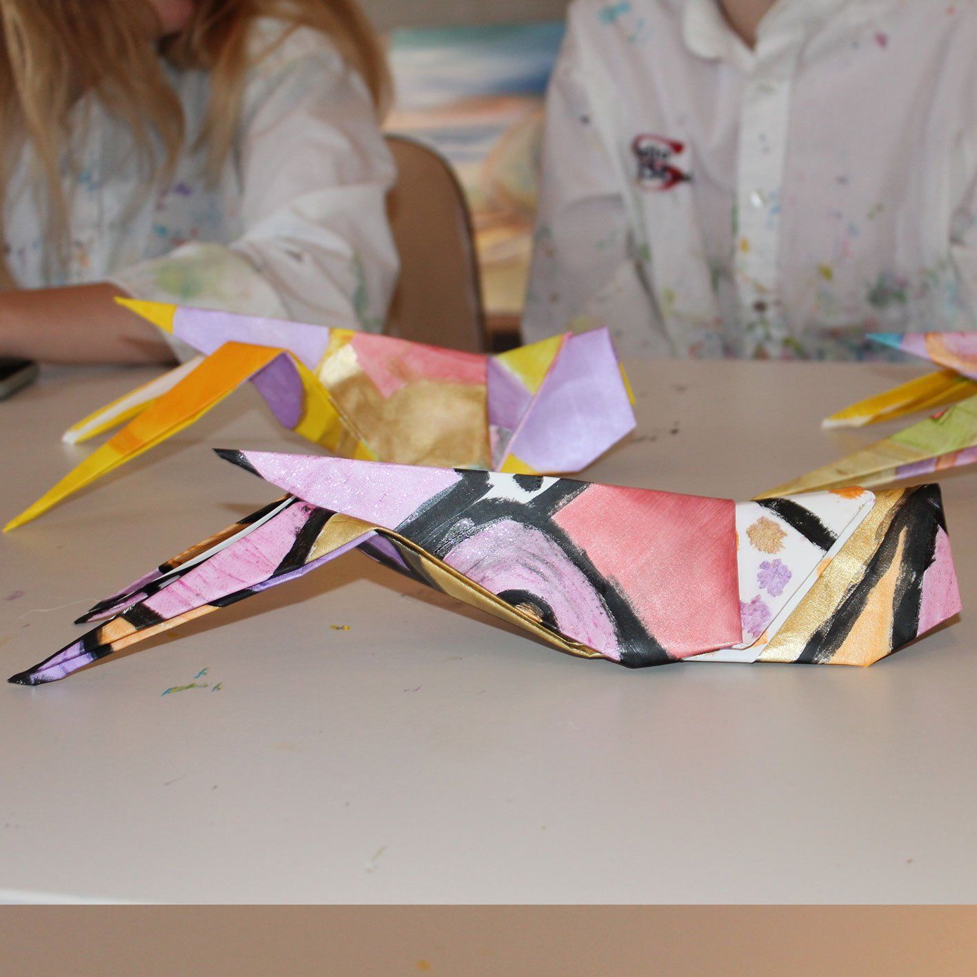 Een kleurrijke origamisprinkhaan zit op een tafel