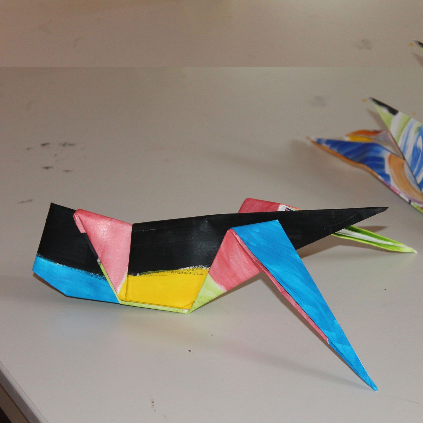 Een kleurrijke origamivogel zit op een tafel