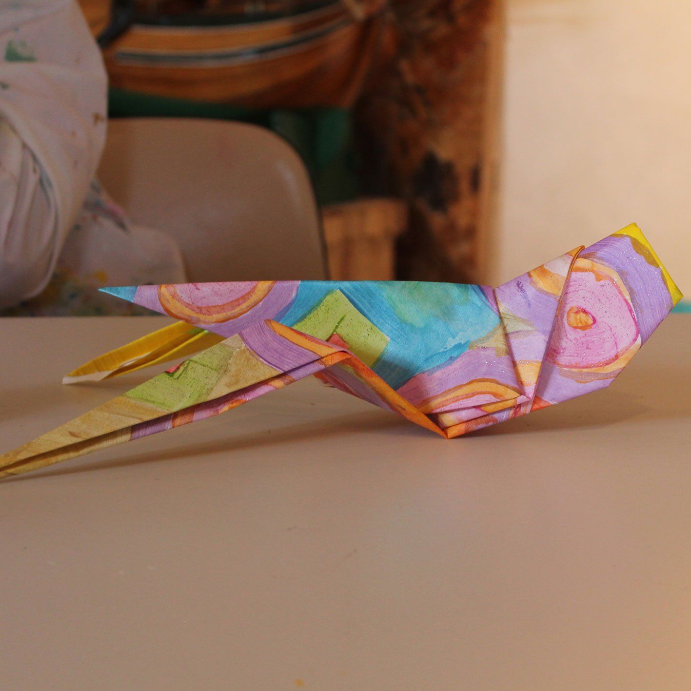 Een kleurrijke origamivogel zit op een tafel