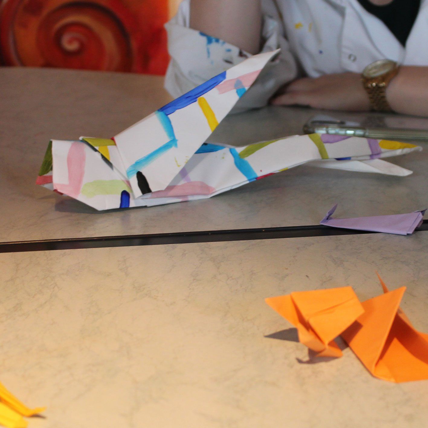 Een persoon die aan een tafel zit met origamivogels erop