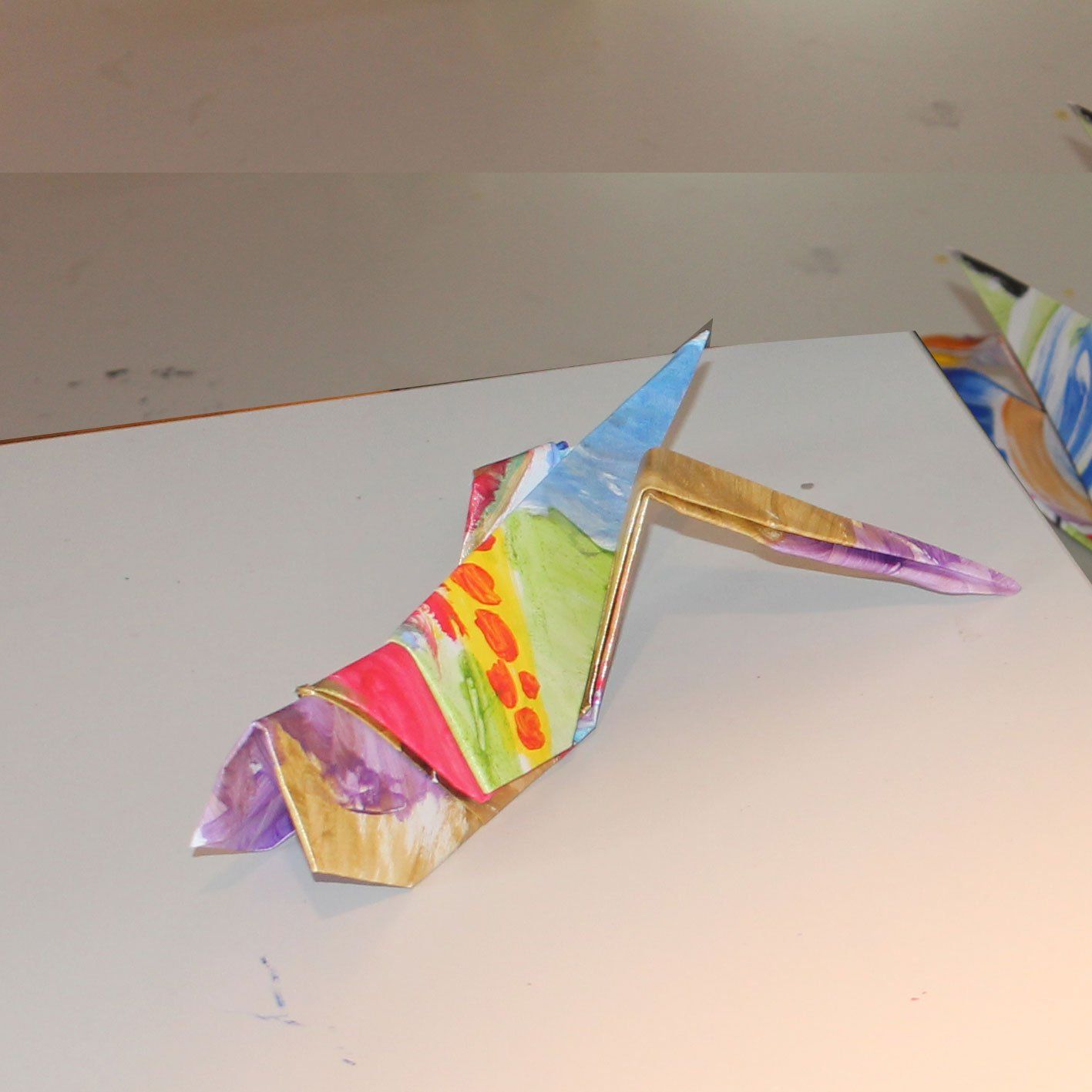 Een kleurrijke origamivogel zit op een wit oppervlak