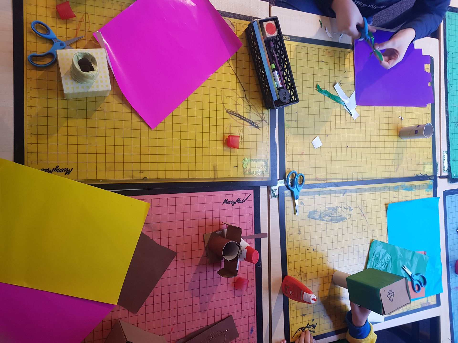 Een kind knipt een stuk roze papier met een schaar