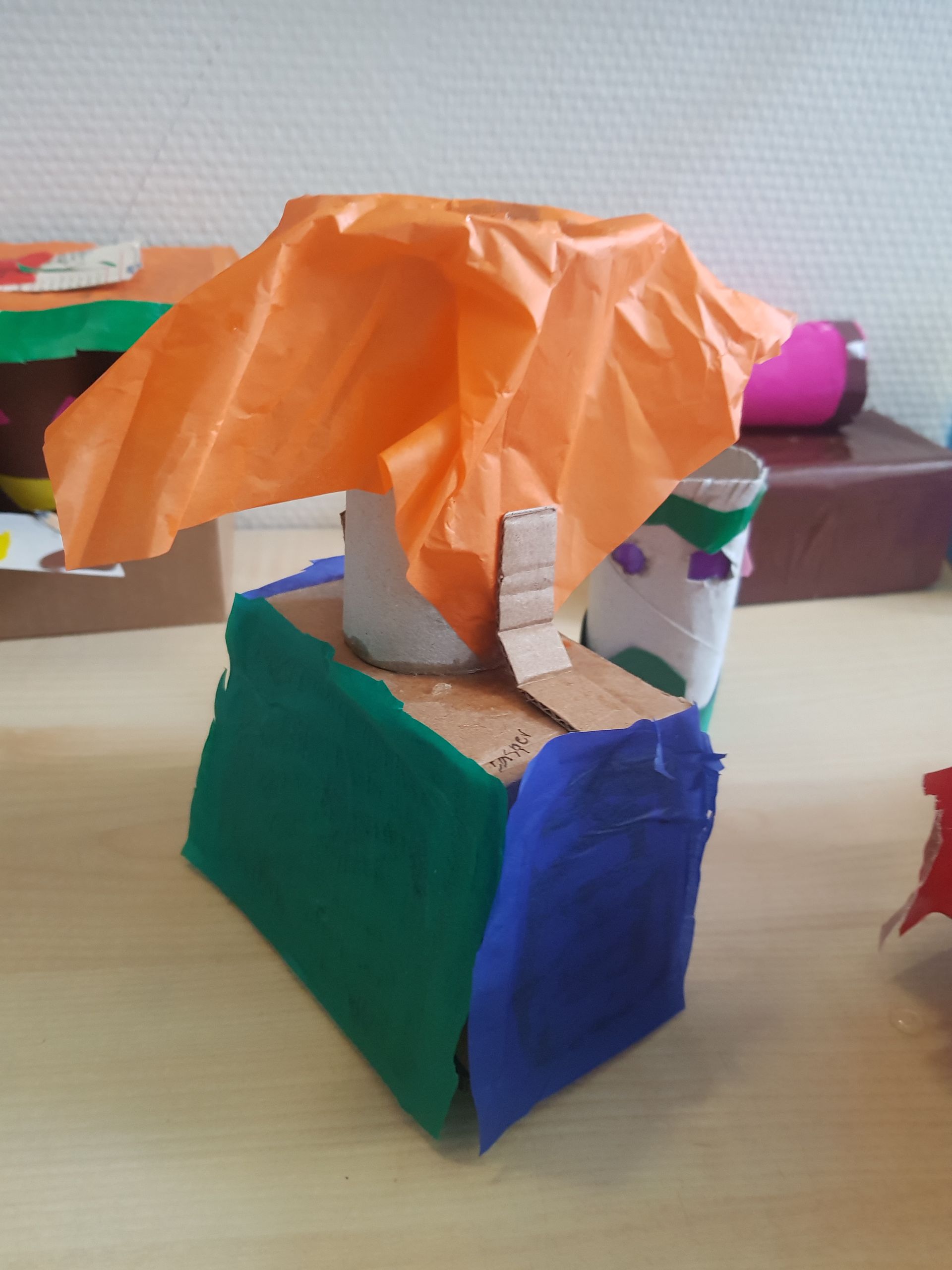 Een sculptuur gemaakt van karton en vloeipapier staat op een tafel