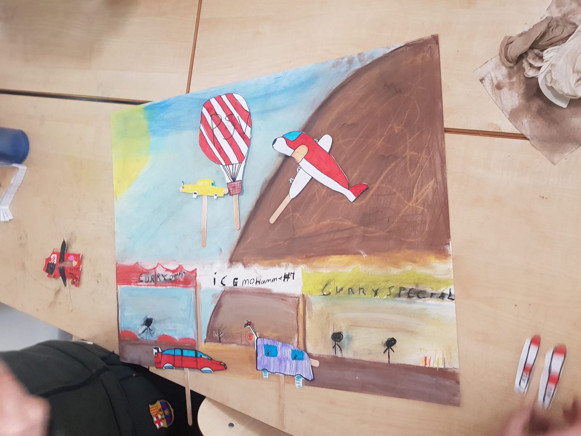 Een kindertekening van een vliegtuig en een luchtballon en voertuigen