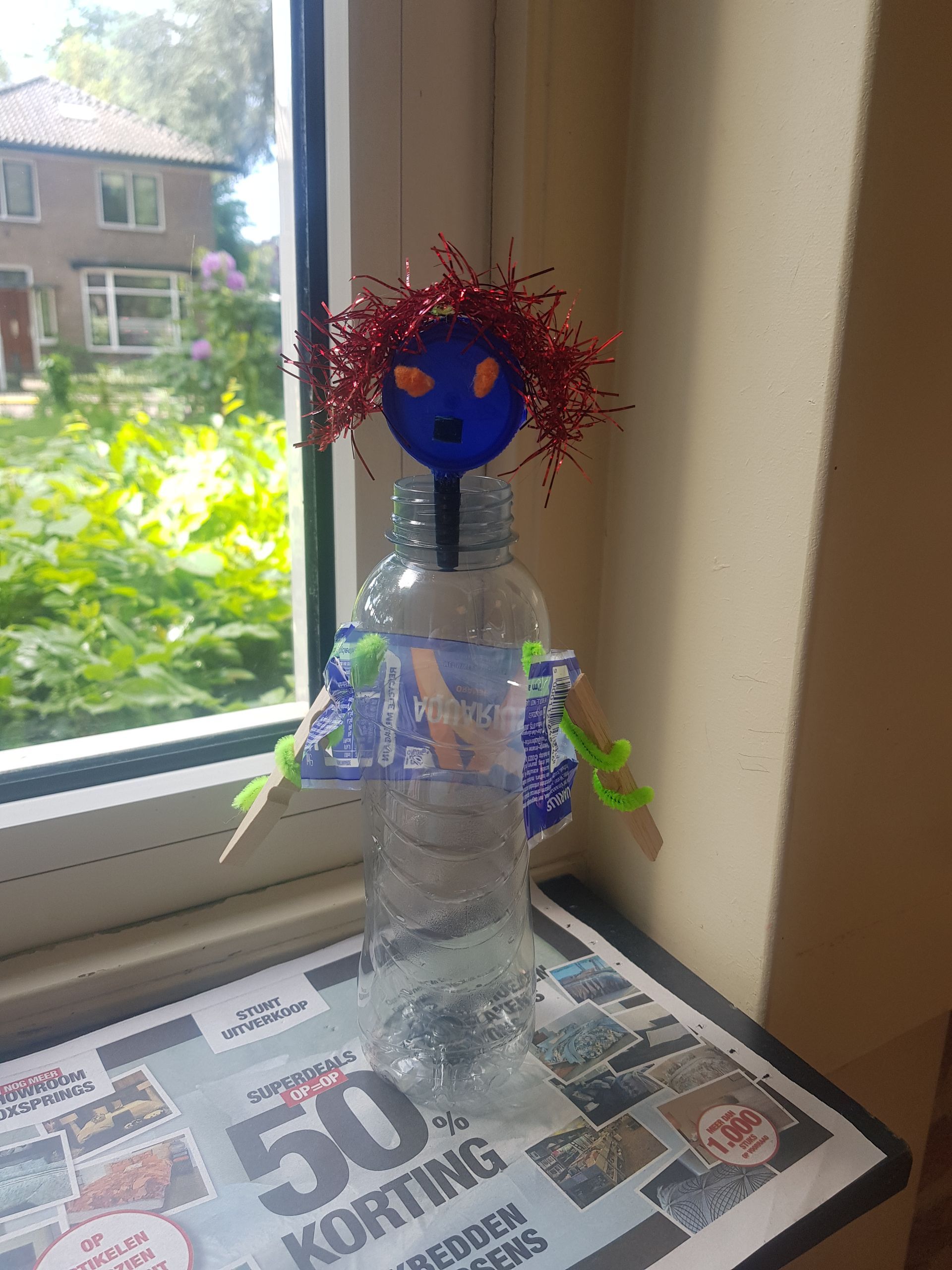 Kunstles in Harderwijk - Een pop gemaakt van een plastic fles staat op een tafel naast een raam