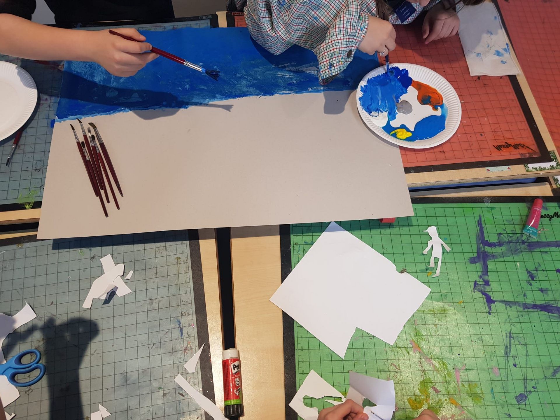 Een leerling schildert met een penseel op een stuk papier