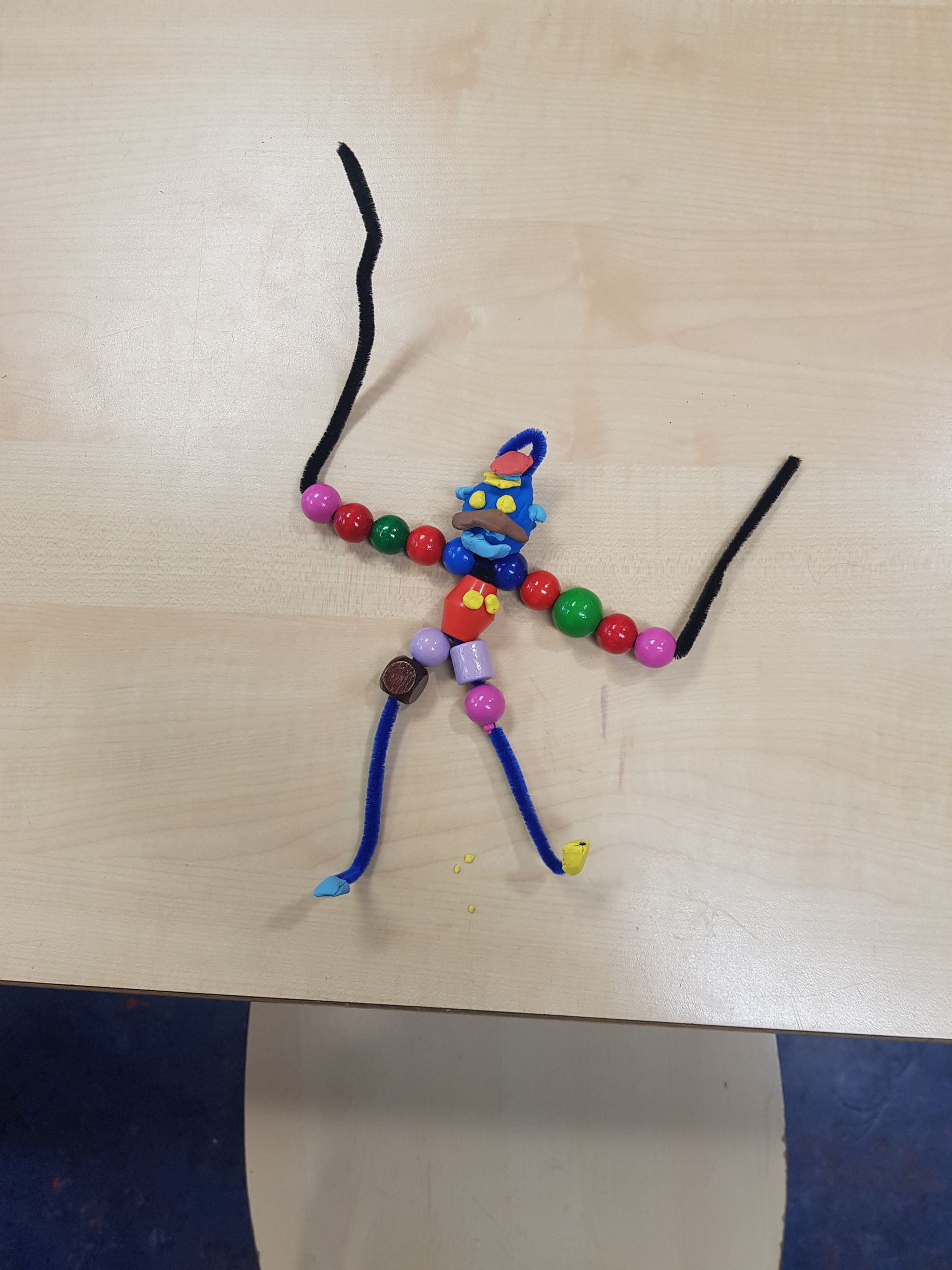 Een speeltje gemaakt van pijpenragers en kralen op een tafel