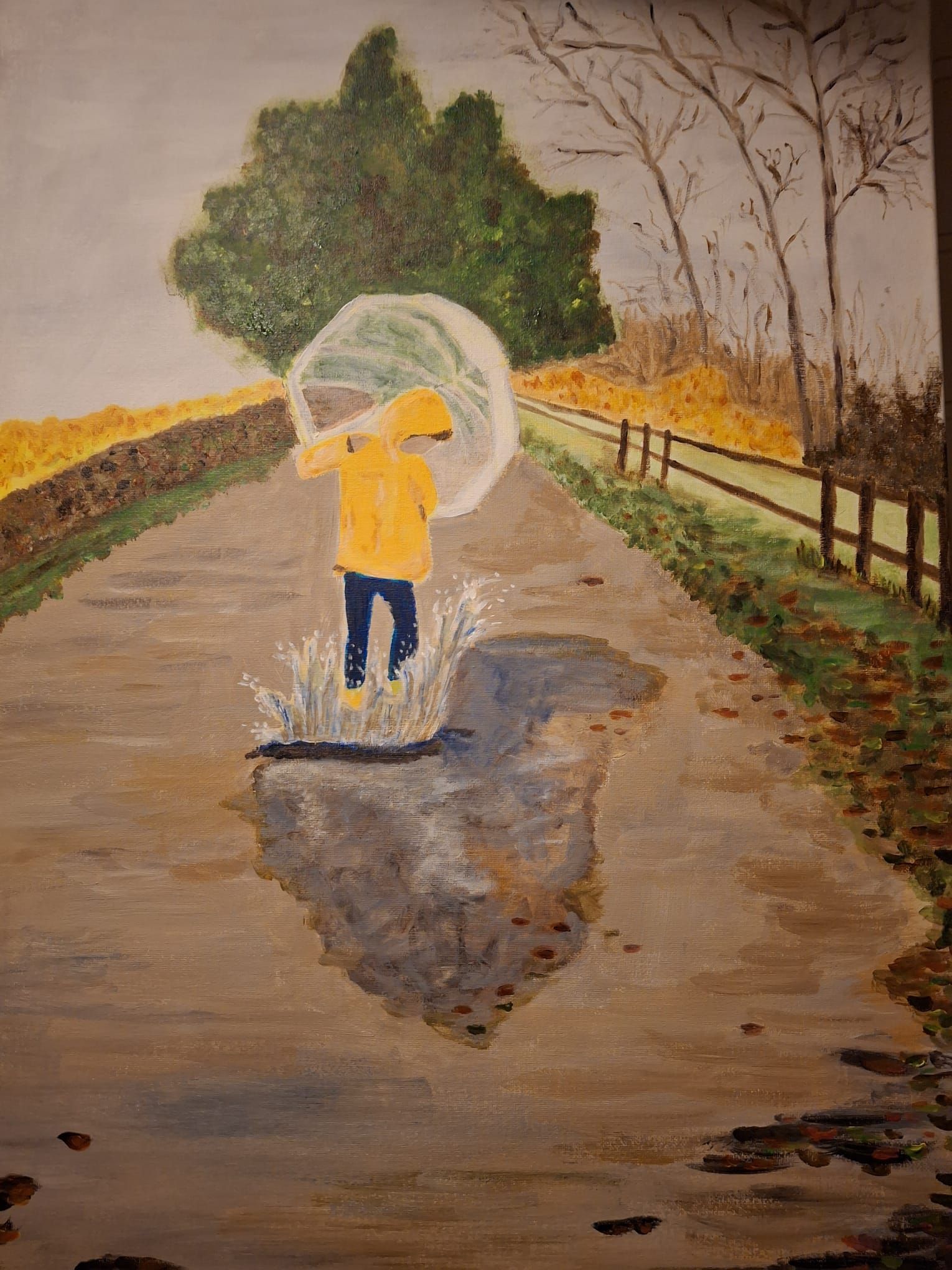 Kind in gele regenjas en laarzen spettert in een plas op een natte weg, met een paraplu in de hand. Herfstlandschap.